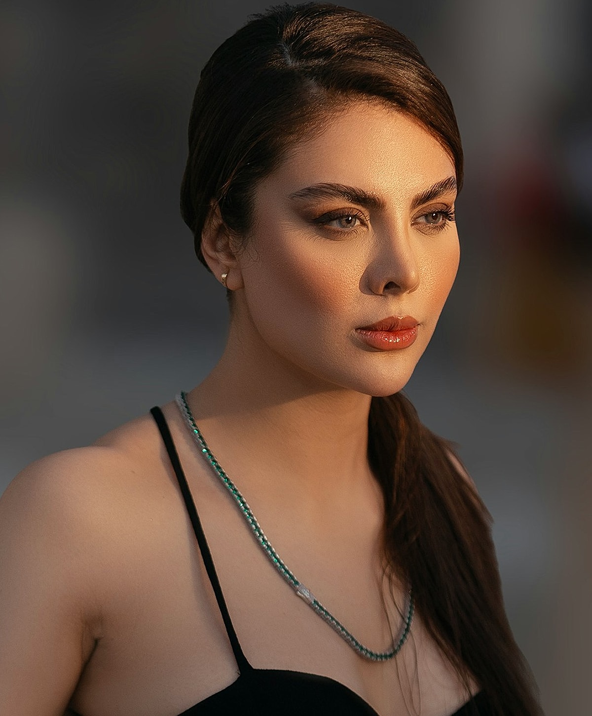 Woman with elegant jewelry in soft sunlight.