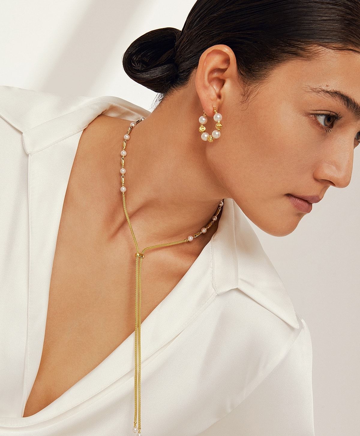 Model wearing elegant jewelry with a white blouse.