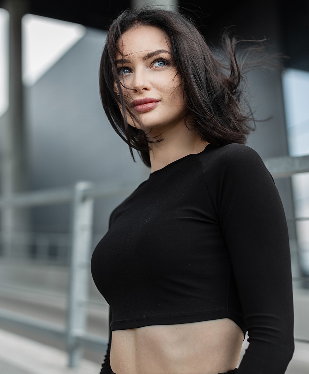 Young woman in black top looking thoughtfully upward.