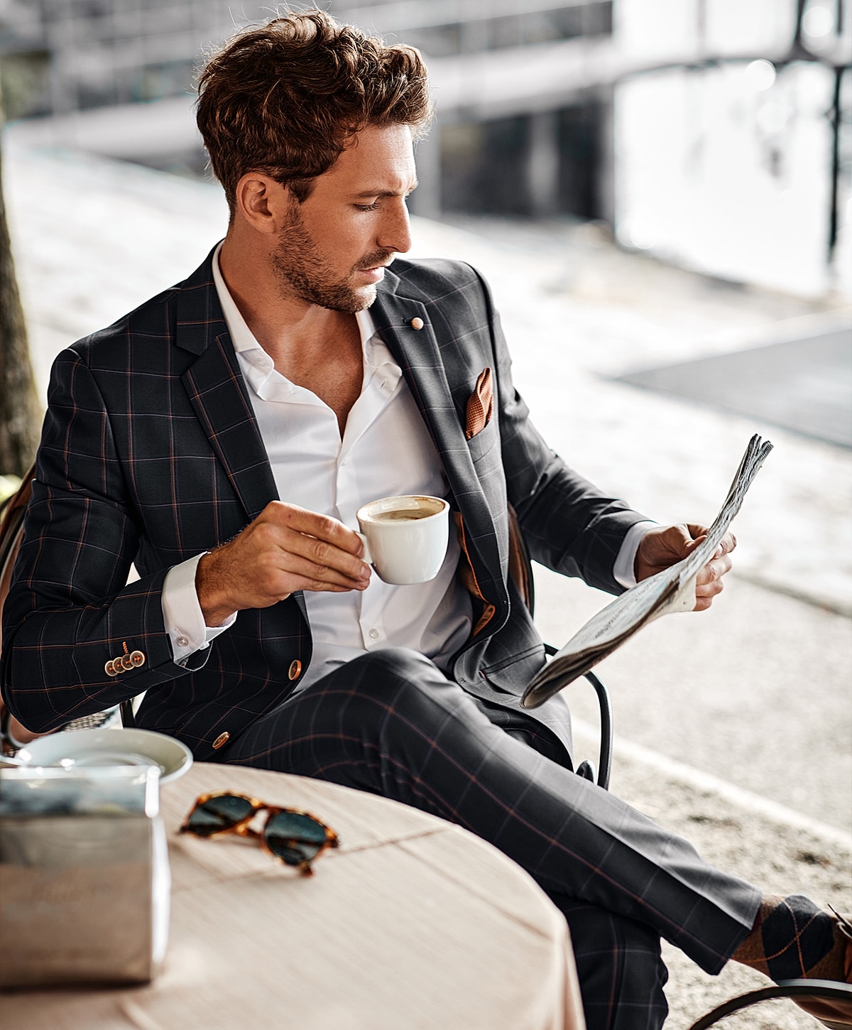 Man in suit enjoying coffee and reading newspaper.