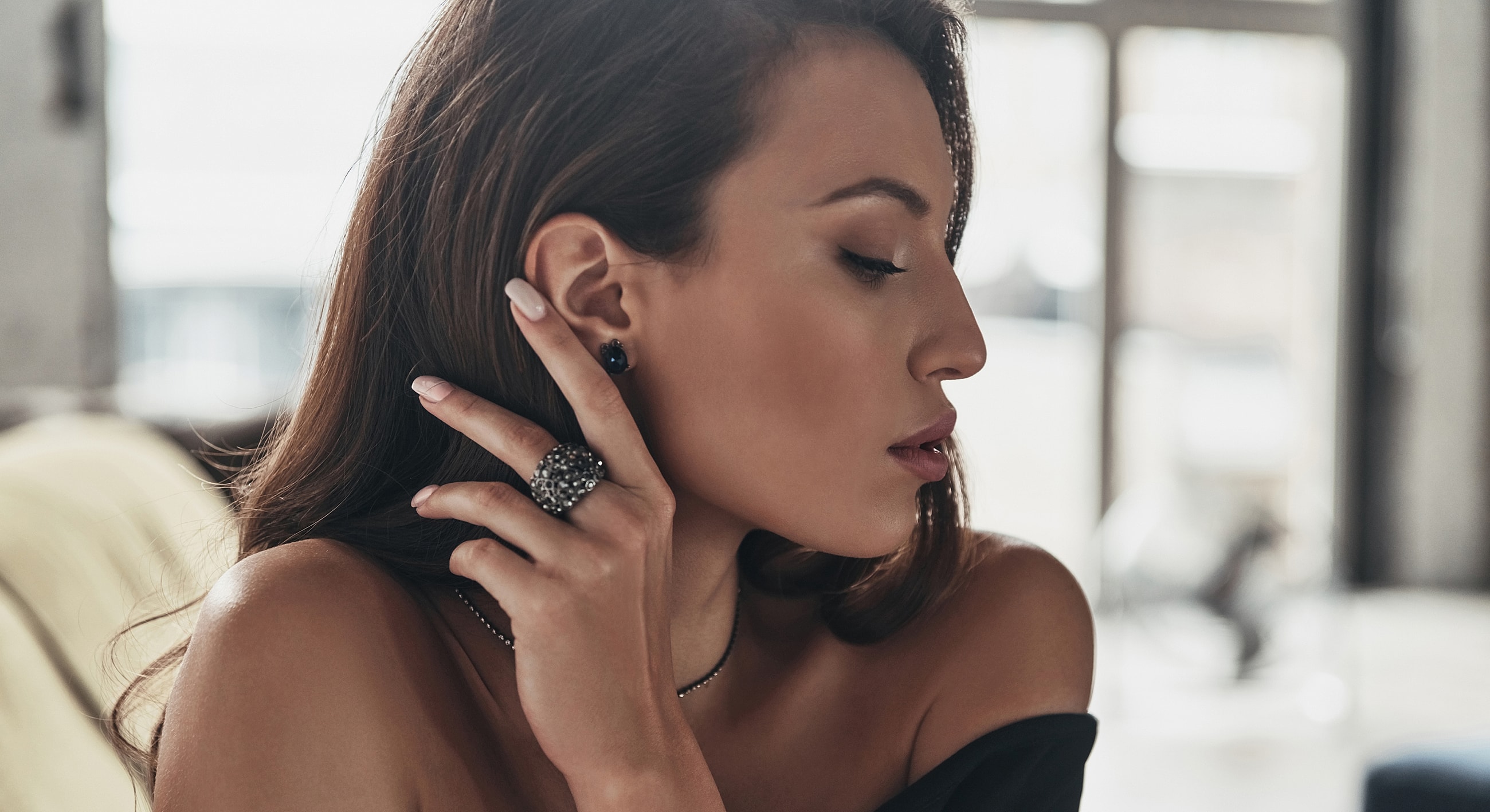 Woman modeling elegant jewelry in soft lighting.